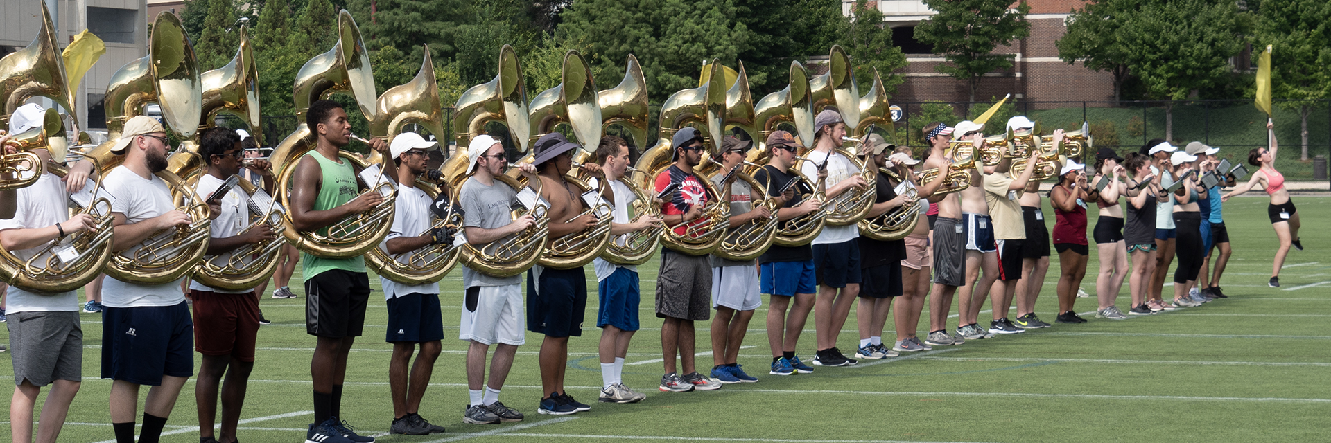 Plain clothes students practicing for a marching band performance in a field.
