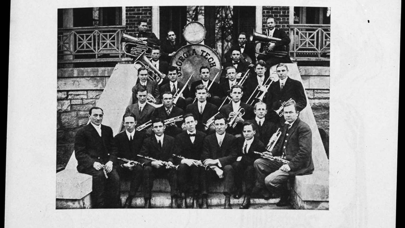 Members of the band posing on steps with their instruments while wearing dark suits.