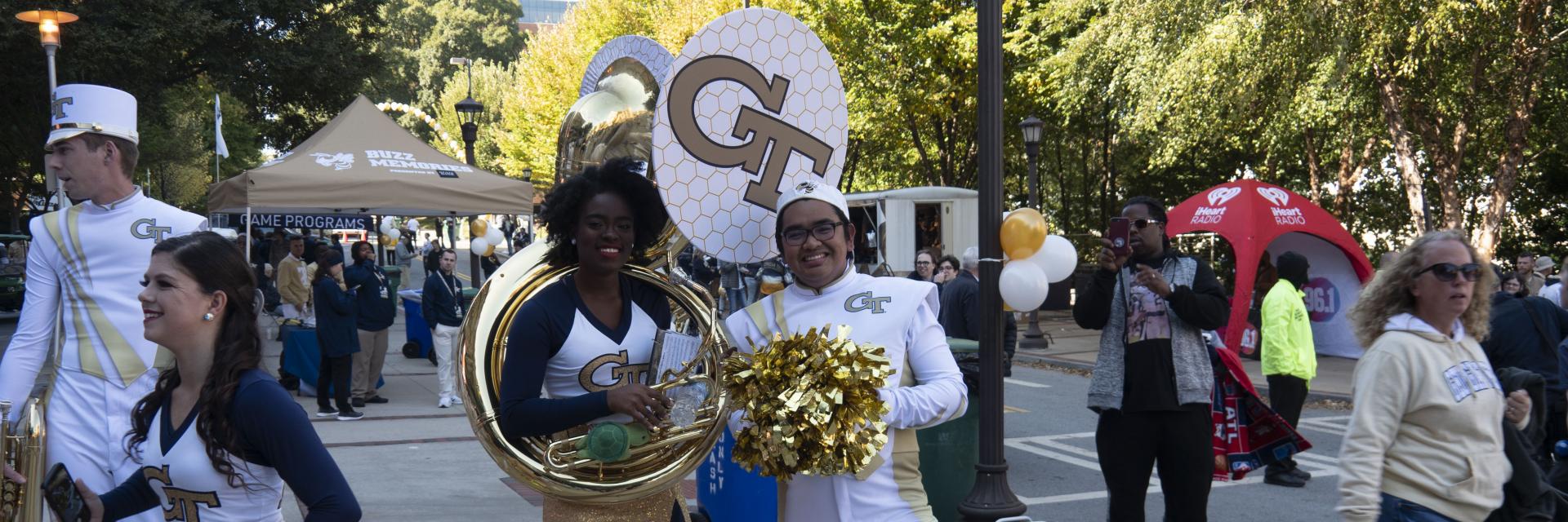 A cheerleader and a tuba player trade instrument and pom poms to pose for a picture.