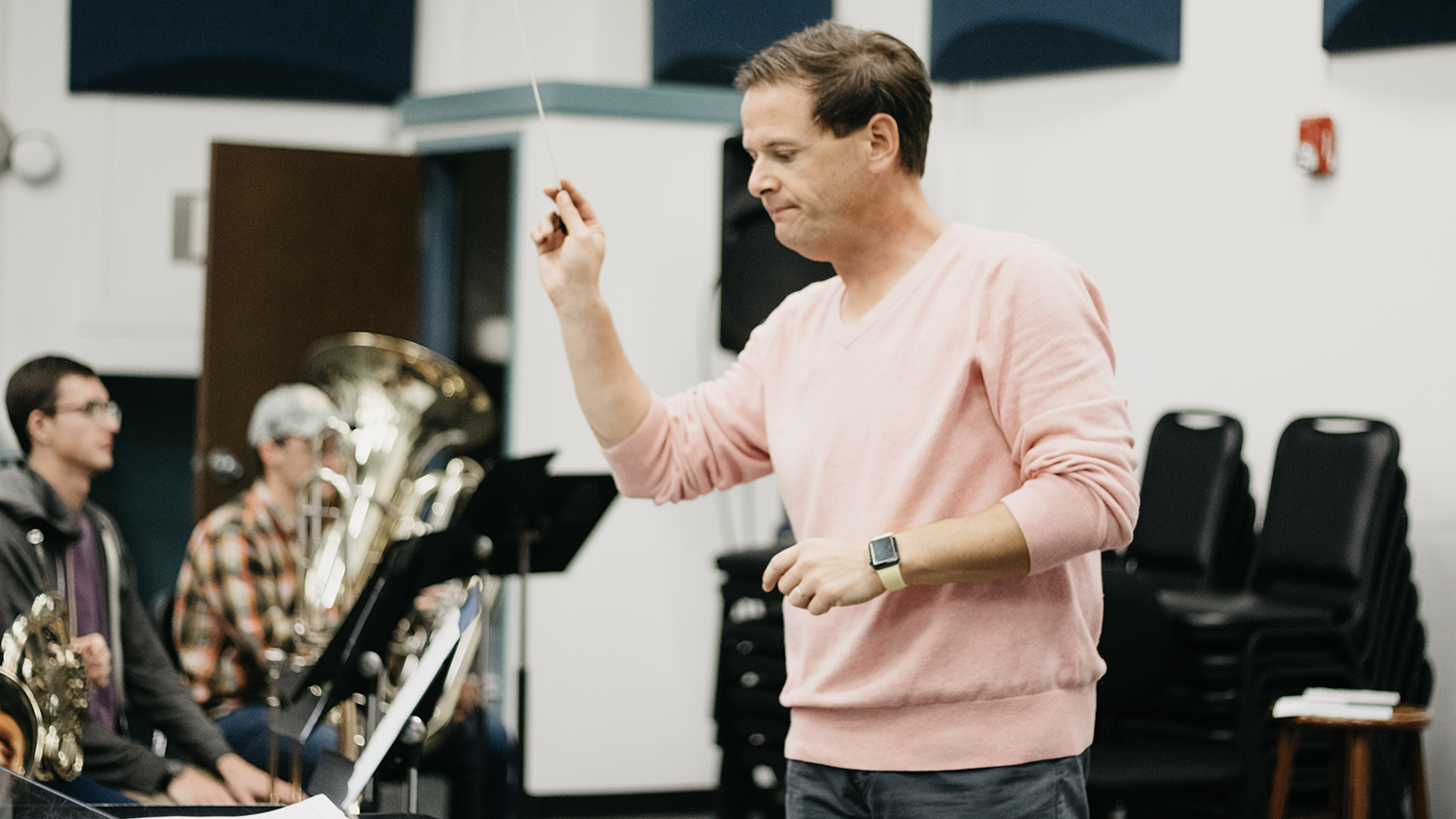 Benjamin Diden directing a band during a rehearsal session.